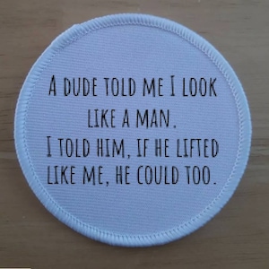 Peut inclure: Patch rond en tissu blanc avec du texte noir qui dit : "Un mec m'a dit que j'avais l'air d'un homme. Je lui ai dit que s'il soulevait comme moi, il pourrait aussi."