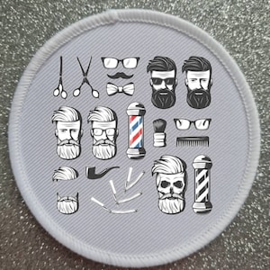 May include: A white round patch with a gray background featuring a variety of black and white illustrations related to a barber shop. The illustrations include a barber pole, scissors, razors, combs, a pipe, a mustache, glasses, and several different styles of beards.