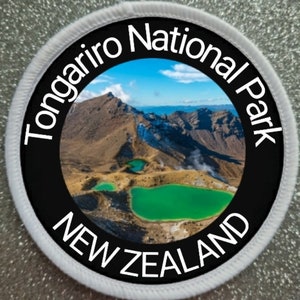 May include: A white and black circular patch with the text "Tongariro National Park NEW ZEALAND" around a photo of a mountain range with green lakes.
