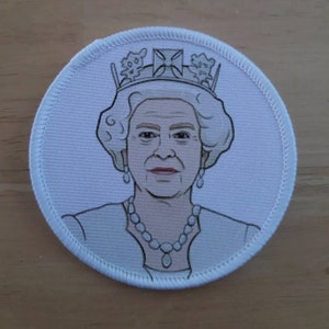 Könnte beinhalten: Ein weißer Stoff-Patch mit einer Schwarzweiß-Illustration von Königin Elisabeth II., die eine Krone und eine Halskette trägt. Der Patch hat einen weißen Rand mit einem genähten Rand.