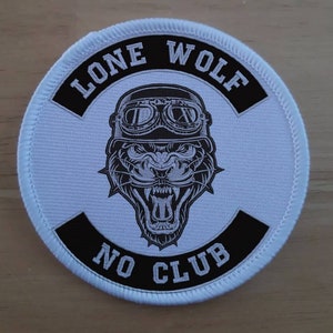 May include: White round patch with black trim. The patch features a black and white illustration of a panther wearing goggles with the text "Lone Wolf No Club" around the image.