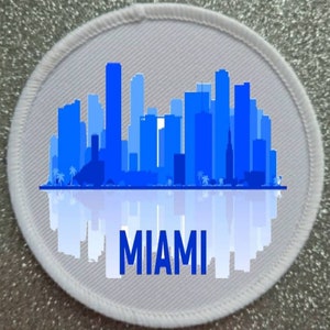 May include: White round patch featuring a blue silhouette of the Miami skyline with the word "MIAMI" printed beneath.