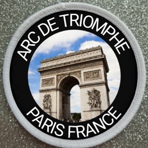 Op de afbeelding: Een witte ronde patch met een zwarte cirkel in het midden. De zwarte cirkel heeft de tekst "ARC DE TRIOMPHE PARIS FRANCE" rond de rand. Het midden van de zwarte cirkel heeft een foto van de Arc de Triomphe in Parijs, Frankrijk.