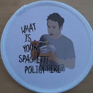 Puede incluir: Un parche redondo blanco con una imagen en blanco y negro de una persona sosteniendo una caja y el texto "WHAT IS YOUR SPAGHETTI POLICY HERE?"
