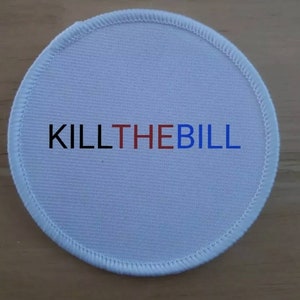 May include: White round fabric patch with the text "KILL THE BILL" in black, red, and blue lettering.