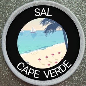 May include: A white round patch with black text and a black circle in the centre. The text reads "SAL CAPE VERDE". The circle contains a beach scene with palm trees, sailboats, and pink umbrellas.