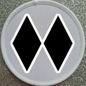 May include: White round patch with a black diamond pattern. The pattern is made up of two overlapping diamonds.