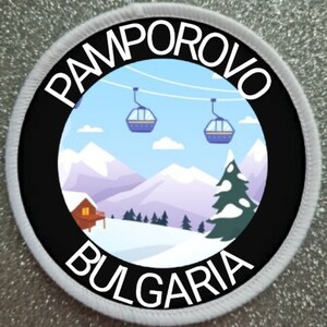 May include: A black and white circular patch with the text "PAMPOROVO BULGARIA" around the edge. The centre of the patch features a cartoon illustration of a snowy mountain scene with a cabin, a pine tree, and three ski lifts.