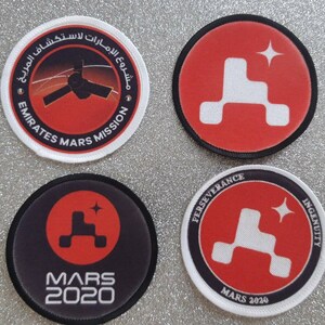 May include: Four round embroidered patches with red, white, and black designs. The patches feature the logos of the Mars 2020 missions: Perseverance, Ingenuity, Emirates Mars Mission, and Mars 2020.
