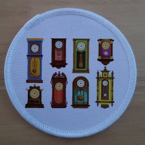 May include: A white round patch featuring nine antique clocks in a variety of colours and styles. The clocks have different coloured faces and hands.