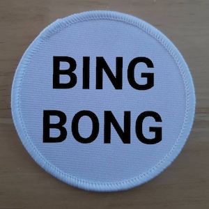 May include: White round fabric patch with black text that reads "BING BONG".
