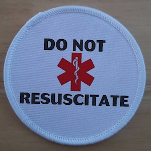 May include: White round patch with black text that reads "DO NOT RESUSCITATE" and a red medical symbol with a snake wrapped around a staff.