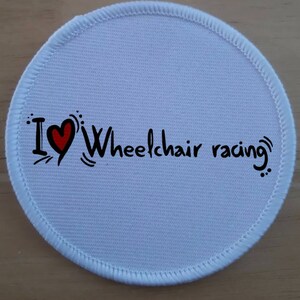 May include: White round fabric patch with a red heart and the text "I ♥ Wheelchair racing" in black.