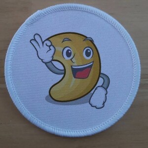 Puede incluir: Un parche redondo blanco con una nuez de la India de dibujos animados haciendo un pulgar hacia arriba. La nuez de la India es amarilla con una cara sonriente y una boca roja.