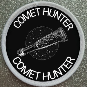 May include: Black and white embroidered patch with a telescope and the text "Comet Hunter" repeated twice.