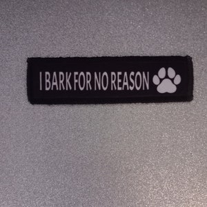 Może przedstawiać: Czarno-biała łatka dla psa z tekstem "Szczekam bez powodu" i białą odbitką łapy.