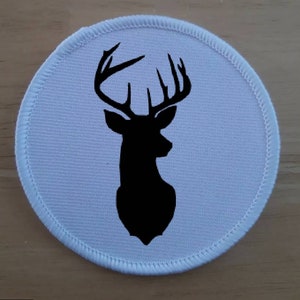 May include: White round fabric patch with a black silhouette of a deer head with antlers.