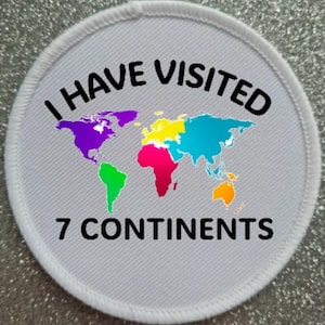 May include: A circular white embroidered patch featuring a colorful world map with continents in purple, green, yellow, pink, blue, and orange. The black text reads I HAVE VISITED 7 CONTINENTS, with the words arched above and below the map design.