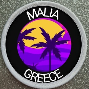 May include: A white round patch with black text and a colourful graphic. The text reads "MALIA GREECE". The graphic is a sunset with palm trees.