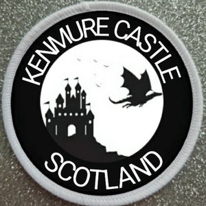 Könnte beinhalten: Schwarzer und weißer runder Patch mit dem Text "Kenmure Castle Scotland" am Rand. Im Inneren des Kreises befindet sich eine schwarze Silhouette eines Schlosses mit einem davonfliegenden Drachen.