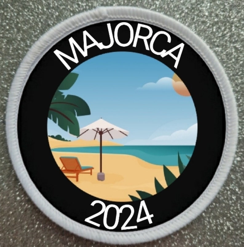 Puede incluir: Parche circular con borde negro y borde cosido blanco. El parche presenta la palabra "MAJORCA" sobre una escena de playa con una sombrilla, una tumbona y el a&ntilde;o "2024". El fondo muestra un cielo azul, el oc&eacute;ano y arena.