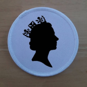 Könnte beinhalten: Weißer Stoff-Patch mit einer schwarzen Silhouette einer Person mit einer Krone.