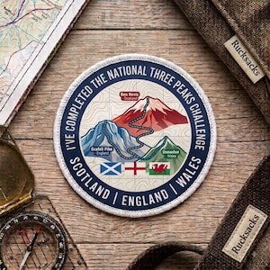 Może przedstawiać: Okrągła haftowana naszywka z napisem I'VE COMPLETED THE NATIONAL THREE PEAKS CHALLENGE. Przedstawia trzy góry o nazwach Ben Nevis, Scafell Pike i Snowdon oraz flagi Szkocji, Anglii i Walii umieszczone w dolnej części grafiki.