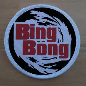 May include: A white round patch with black and white swirling design and the words "Bing Bong" in red.