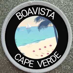 May include: A white round patch with black text and a beach scene. The text reads "BOAVISTA CAPE VERDE". The scene shows a beach with palm trees, sailboats, and pink umbrellas.