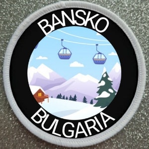 Könnte beinhalten: Ein runder weißer und schwarzer Patch mit dem Text "Bansko Bulgarien" in weißen Buchstaben auf schwarzem Hintergrund. Die Mitte des Patches zeigt eine Cartoon-Illustration einer verschneiten Berglandschaft mit einer Hütte, Bäumen und Skiliften.