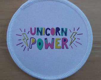 May include: White round fabric patch with a colourful graphic that says "Unicorn Power" with lightning bolts on either side.