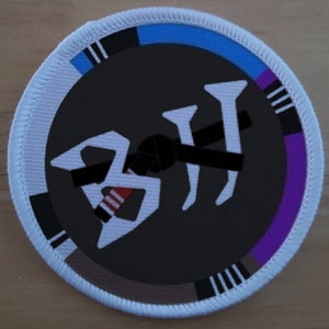 Puede incluir: Parche redondo blanco con un gráfico negro, blanco y rojo de la palabra "BJJ" en una fuente estilizada. El parche tiene un borde negro, blanco, azul y morado.