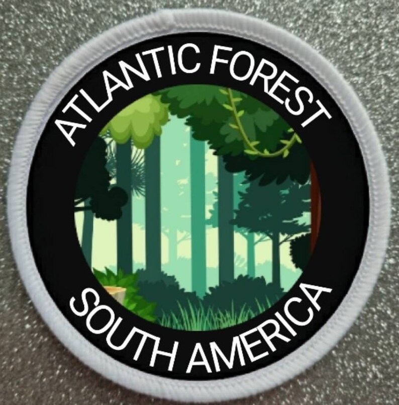 May include: Round patch with a black border and white stitching. The patch shows a forest scene in shades of green and a black ring with the words "ATLANTIC FOREST" and "SOUTH AMERICA" in white.