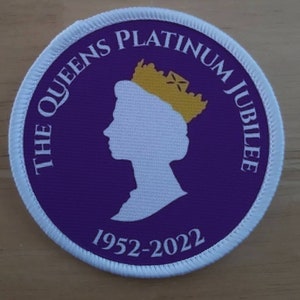 Könnte beinhalten: Ein runder Aufnäher mit einem lila Zentrum und weißem Rand. Der Text "THE QUEENS PLATINUM JUBILEE" ist oben in Weiß. Eine weiße Silhouette eines gekrönten Kopfes befindet sich in der Mitte. Die Jahre "1952-2022" stehen unten.