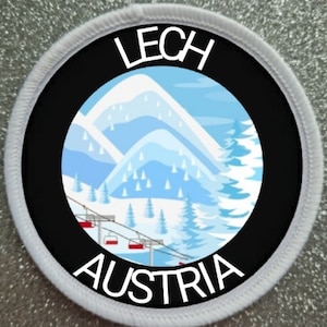 Könnte beinhalten: Ein kreisförmiger Aufnäher mit den Worten "LECH AUSTRIA" in weißer Schrift. Der Aufnäher zeigt eine Winterszene mit schneebedeckten Bergen, Kiefern und einem Skilift. Der Aufnäher hat einen schwarzen Hintergrund und einen weißen Rand.