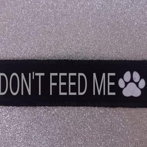 May include: Black fabric patch with white text that reads "DON'T FEED ME" and a white paw print.