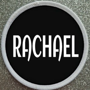May include: White circle patch with a white border. The patch has a black background with the name "RACHAEL" written in white.