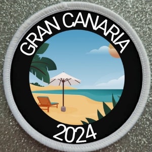 Könnte beinhalten: Ein weißer und schwarzer runder Patch mit dem Text "GRAN CANARIA 2024" am Rand. Die Mitte des Patches zeigt eine Strandszene mit einer Palme, einem Sonnenschirm, einem Liegestuhl und dem Meer.