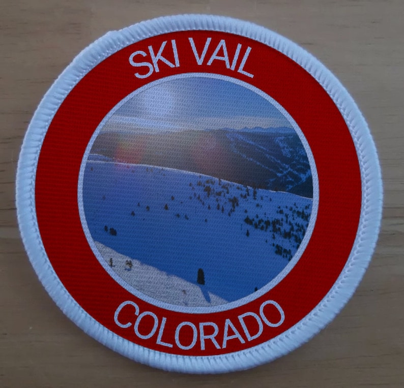 May include: A white and red circular patch with the text "SKI VAIL COLORADO" and a photo of a snowy mountain landscape.