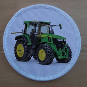 May include: A green and black John Deere tractor with a white background. The tractor has large tires and a front loader.