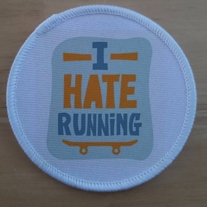 May include: White round patch with a blue and orange graphic that says "I hate running" with a skateboard underneath the text.