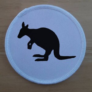 Op de afbeelding: Een ronde witte stoffen patch met een zwart silhouet van een kangoeroe.