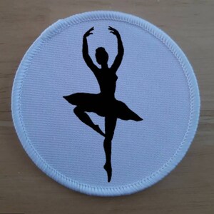 Può includere: Toppa rotonda in tessuto bianco con una silhouette nera di una ballerina in posa di danza.