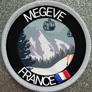 Puede incluir: Parche redondo blanco con borde negro y texto blanco que dice "MEGEVE FRANCE". El centro del parche presenta una ilustración en blanco y negro de una escena de montaña nevada con un telesilla y esquiadores. Una pequeña bandera francesa se encuentra en la esquina inferior derecha.