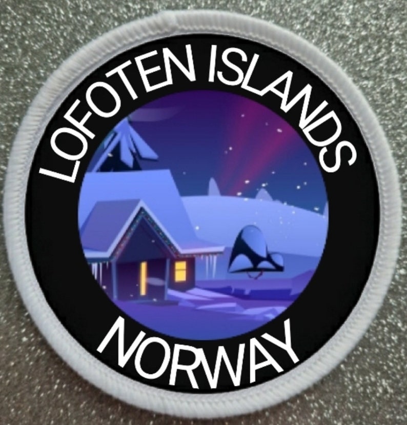 May include: A white circular patch with black text and a black circle in the center. The text reads "Lofoten Islands Norway". The black circle contains a cartoon image of a snowy cabin with a purple sky and a pink aurora borealis in the background.