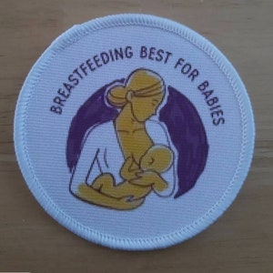 Könnte beinhalten: Ein runder Aufnäher mit dem Text "BREASTFEEDING BEST FOR BABIES", der eine Illustration einer stillenden Mutter umgibt. Das Design hat einen lila Hintergrund und gelbe und weiße Figuren.