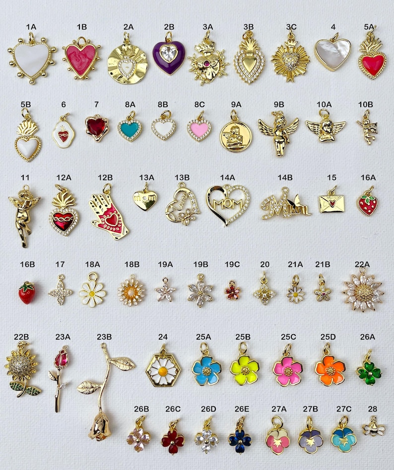 May include: Assortment of 28 gold-tone charms with various designs, including hearts, flowers, religious symbols, and letters. The charms are arranged in rows on a white background.