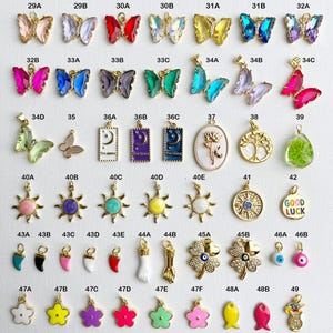 May include: Assortment of colorful charms in various shapes and designs, including butterflies, suns, flowers, and a charm with the words "Good Luck".