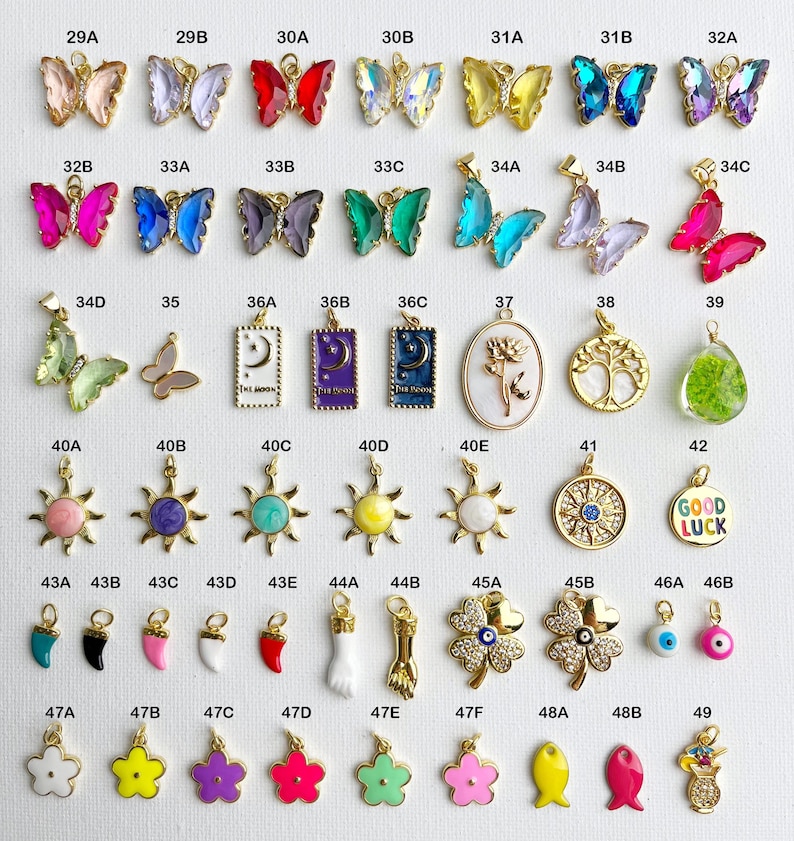 May include: Assortment of colorful charms in various shapes and designs, including butterflies, suns, flowers, and a charm with the words "Good Luck".