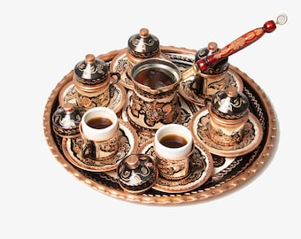 May include: A copper serving tray with a set of six small copper cups and a copper coffee pot with a wooden handle. The cups and pot are decorated with black and white floral designs.